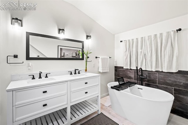 bathroom featuring a tub to relax in, vanity, and vaulted ceiling