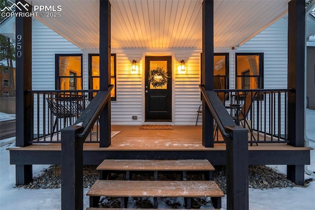 snow covered property entrance featuring covered porch