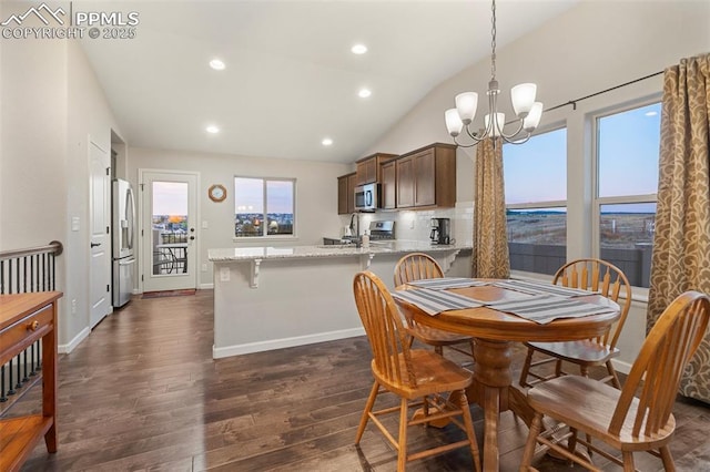 dining room with dark wood-type flooring, vaulted ceiling, and an inviting chandelier