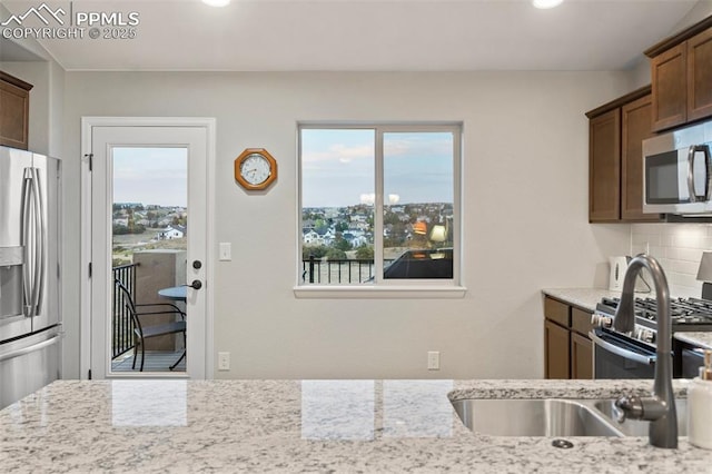 kitchen with plenty of natural light, light stone counters, appliances with stainless steel finishes, and tasteful backsplash