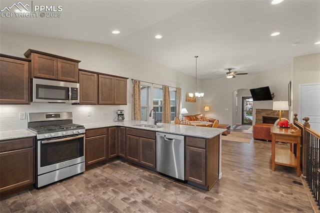 kitchen with lofted ceiling, sink, appliances with stainless steel finishes, dark hardwood / wood-style flooring, and kitchen peninsula