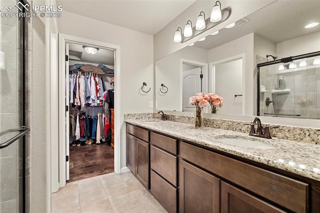 bathroom featuring tile patterned flooring, vanity, and a shower with shower door