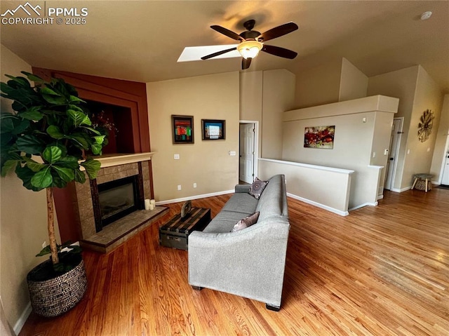 living room featuring light wood-type flooring, lofted ceiling with skylight, and ceiling fan