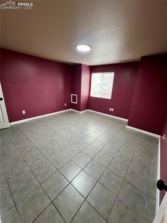 tiled empty room with a textured ceiling