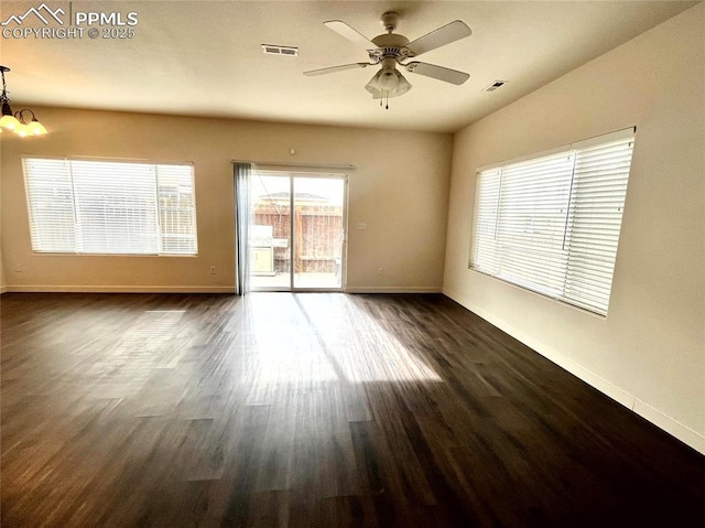 empty room with ceiling fan with notable chandelier and dark wood-type flooring