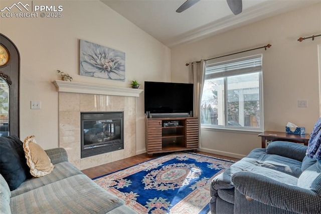 living room featuring ceiling fan, hardwood / wood-style floors, vaulted ceiling, and a fireplace