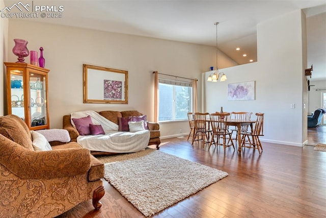 living room with lofted ceiling, a chandelier, and hardwood / wood-style flooring