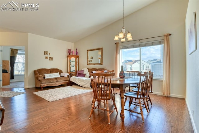 dining area with vaulted ceiling, wood-type flooring, plenty of natural light, and a notable chandelier