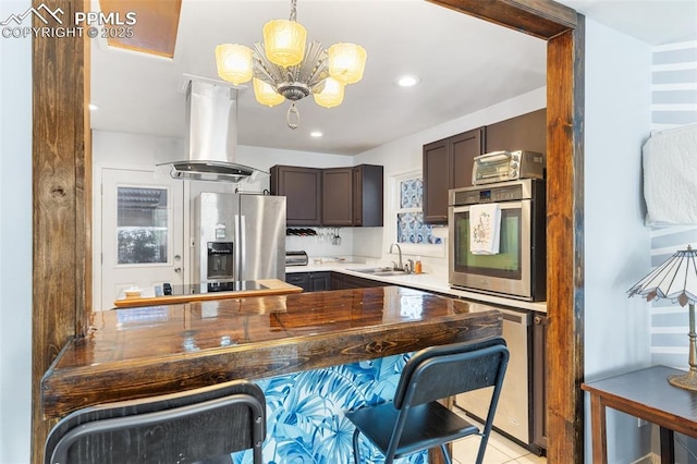 kitchen with sink, wooden counters, appliances with stainless steel finishes, dark brown cabinets, and island exhaust hood