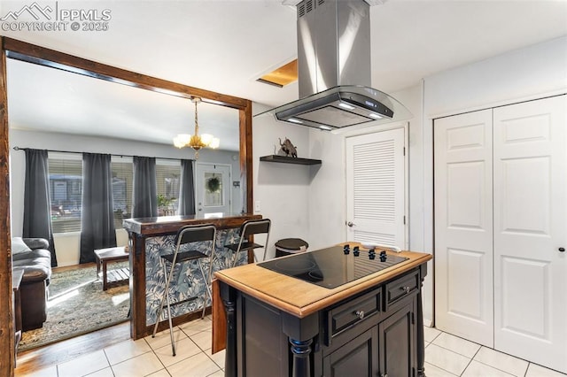 kitchen featuring black electric cooktop, island range hood, pendant lighting, and light tile patterned flooring