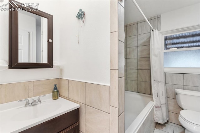 full bathroom with tile walls, shower / bath combination with curtain, tile patterned flooring, vanity, and toilet