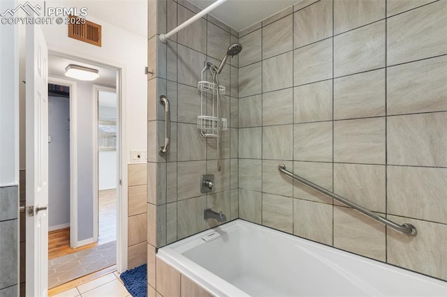 bathroom featuring tiled shower / bath combo and tile patterned flooring