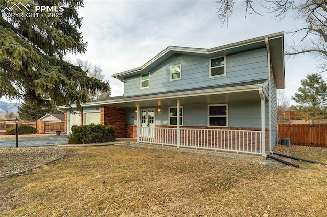 view of front of home with covered porch, a garage, and a front lawn