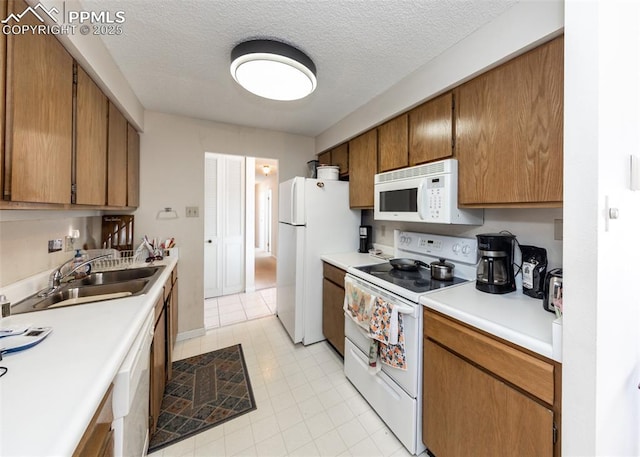 kitchen with sink, white appliances, and a textured ceiling