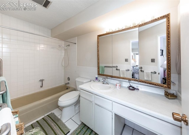 full bathroom featuring tile walls, tile patterned flooring, vanity, a textured ceiling, and tiled shower / bath