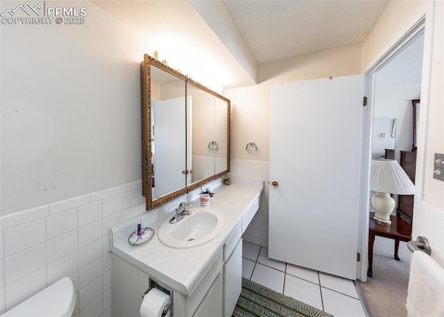 bathroom featuring vanity, tile walls, tile patterned floors, and toilet