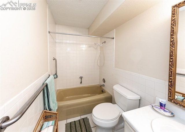 full bathroom with vanity, toilet, a textured ceiling, and tile walls