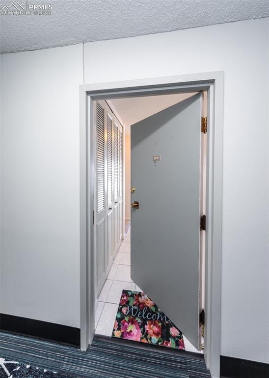 hall with a textured ceiling and light tile patterned floors