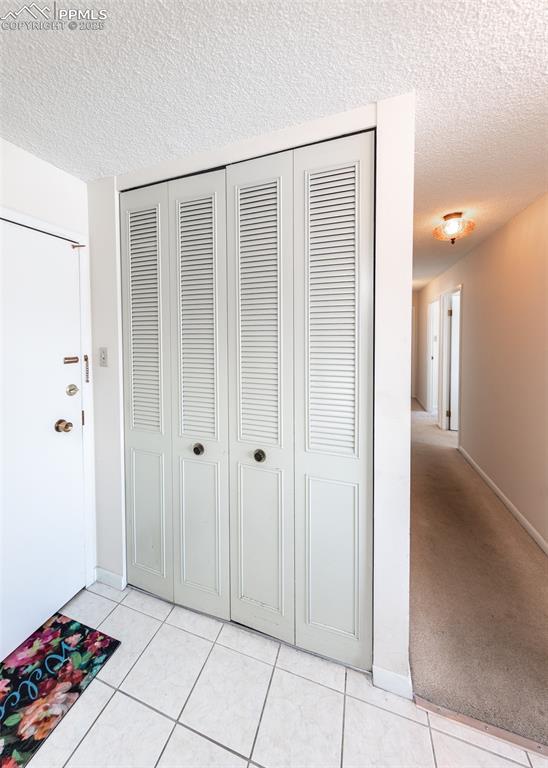 hall featuring light tile patterned floors and a textured ceiling