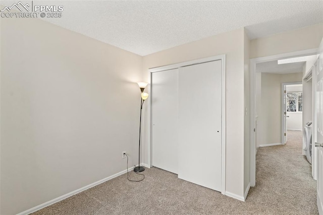 unfurnished bedroom featuring a textured ceiling, light carpet, and a closet