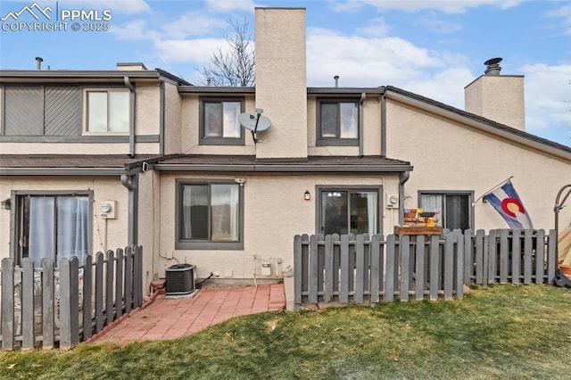 rear view of property featuring central AC unit and a lawn