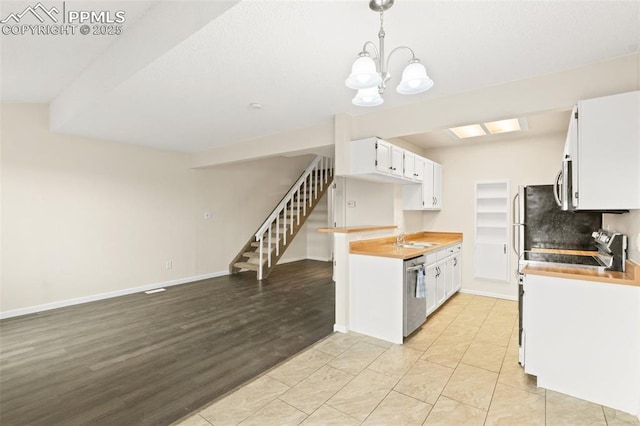 kitchen with sink, white cabinetry, hanging light fixtures, and appliances with stainless steel finishes