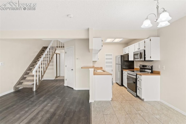 kitchen featuring decorative light fixtures, white cabinetry, butcher block counters, and stainless steel appliances