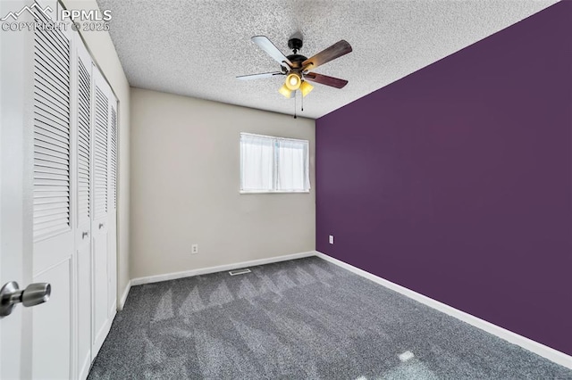 unfurnished bedroom with ceiling fan, a closet, a textured ceiling, and dark colored carpet