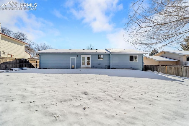 snow covered back of property featuring french doors