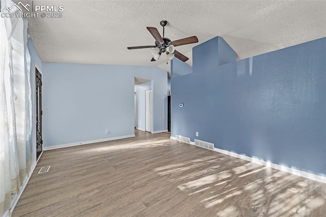 spare room featuring lofted ceiling, ceiling fan, wood-type flooring, and a textured ceiling