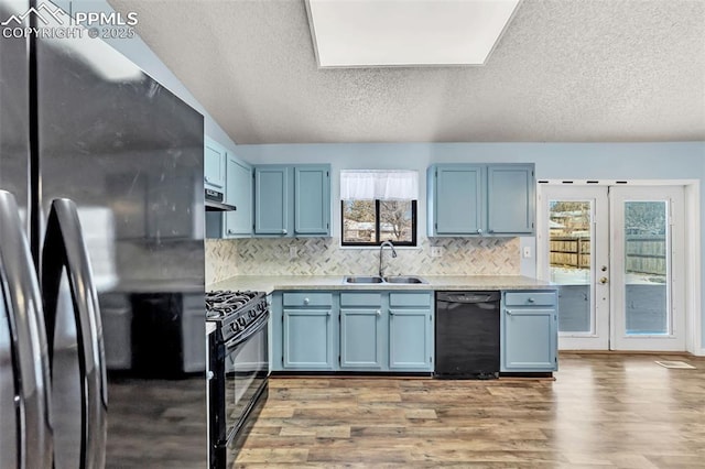 kitchen featuring blue cabinets, sink, hardwood / wood-style floors, and black appliances