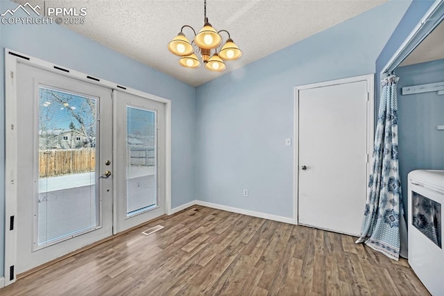 doorway featuring independent washer and dryer, wood-type flooring, french doors, and a textured ceiling