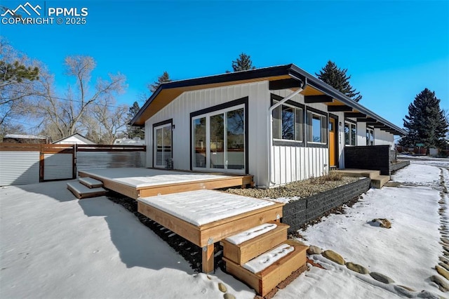 snow covered back of property featuring a wooden deck