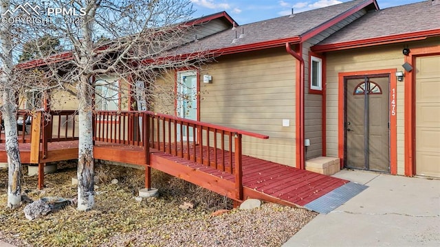 property entrance featuring a garage and a wooden deck