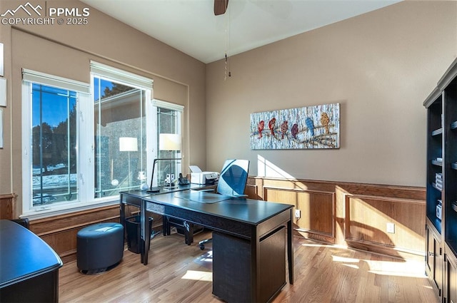 office space featuring ceiling fan, light hardwood / wood-style flooring, and wood walls