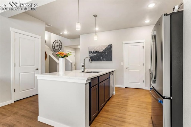 kitchen featuring pendant lighting, sink, light hardwood / wood-style flooring, an island with sink, and stainless steel appliances