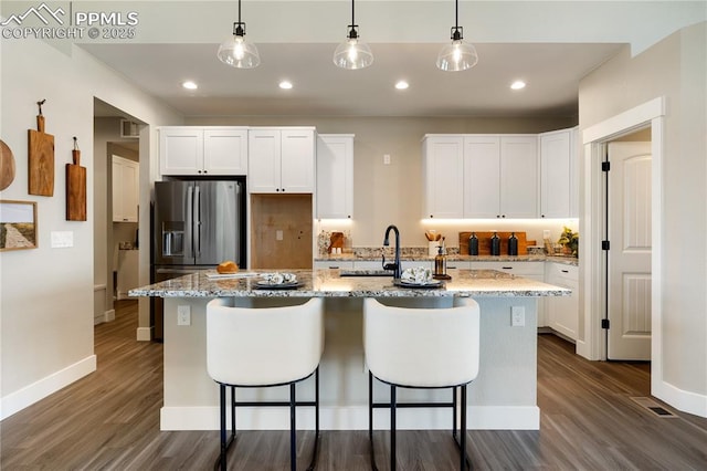 kitchen featuring white cabinets, sink, a center island with sink, and light stone counters