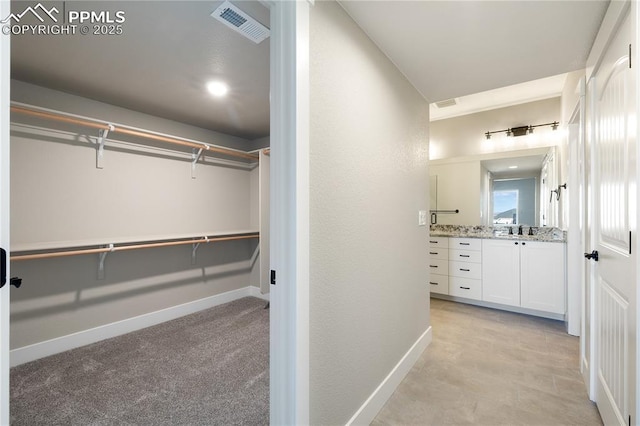 walk in closet featuring light carpet and sink