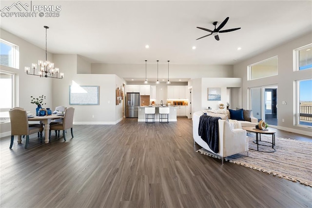 living room featuring ceiling fan with notable chandelier, dark hardwood / wood-style floors, and plenty of natural light