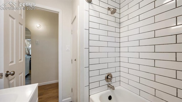 bathroom with wood finished floors, baseboards, and shower / washtub combination