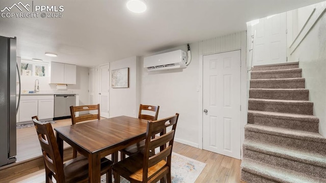 dining area with a wall mounted air conditioner, baseboards, stairs, and light wood finished floors