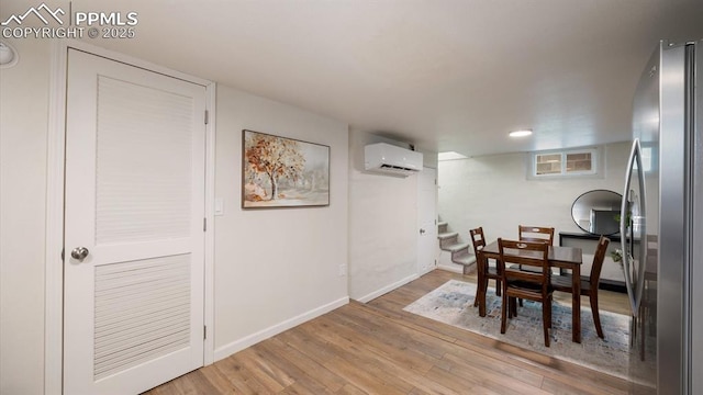 dining space with stairs, baseboards, light wood-type flooring, and a wall mounted AC