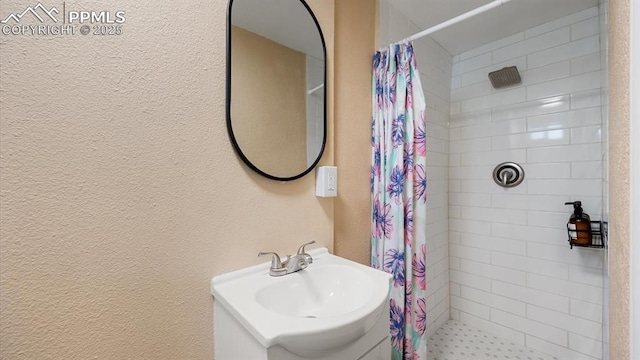 bathroom featuring a shower stall, a textured wall, and a sink