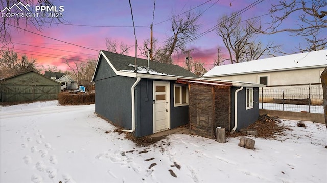 exterior space with an outbuilding, fence, stone siding, and stucco siding