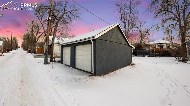 snow covered garage featuring a garage