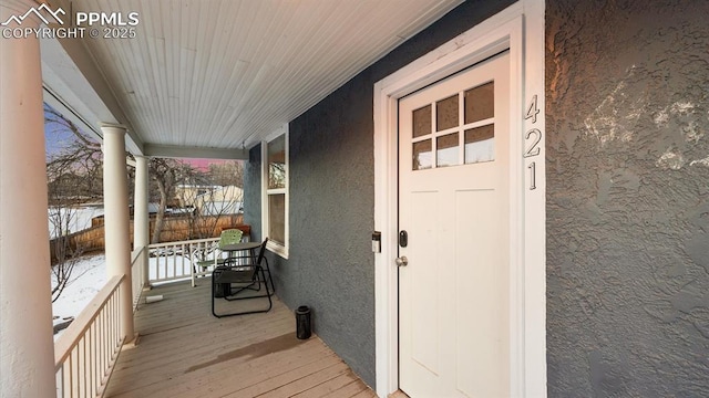 snow covered property entrance with a porch