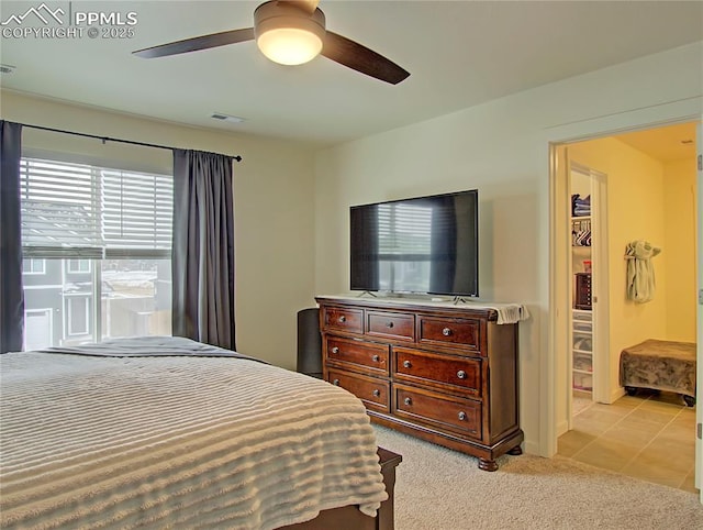 bedroom featuring a walk in closet, ceiling fan, and light carpet