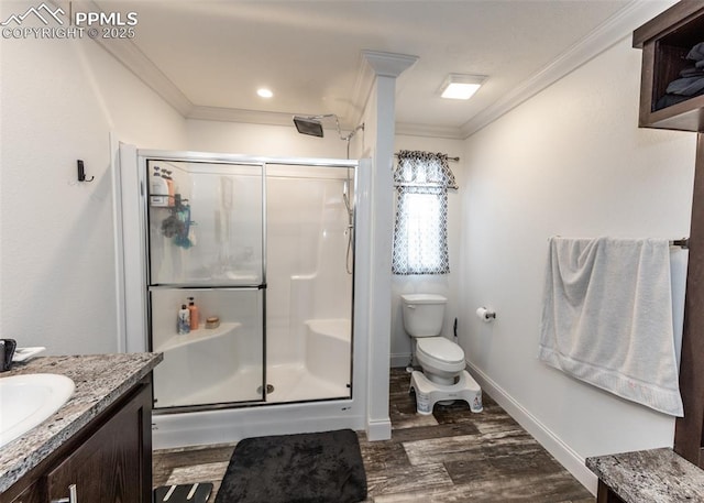 bathroom with vanity, toilet, ornamental molding, and a shower with door