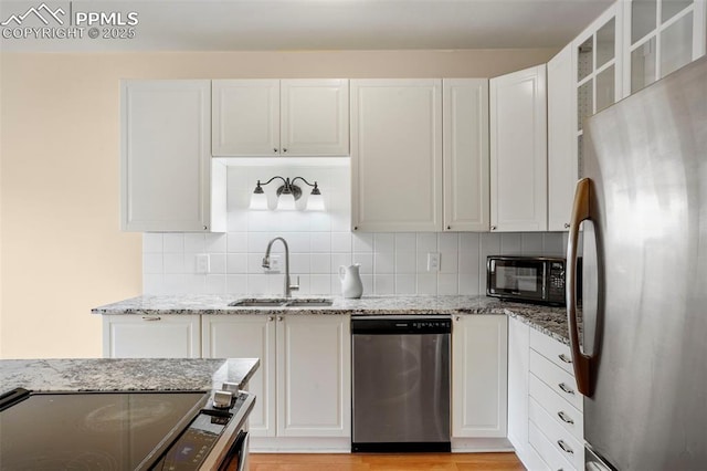 kitchen with white cabinetry, sink, stainless steel appliances, and light stone counters