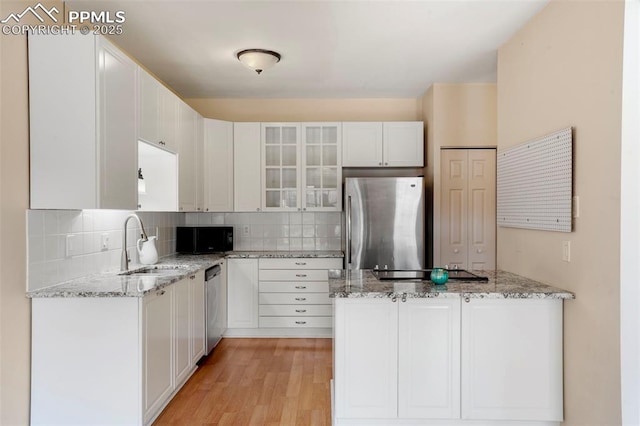 kitchen with sink, black appliances, light stone countertops, decorative backsplash, and white cabinets